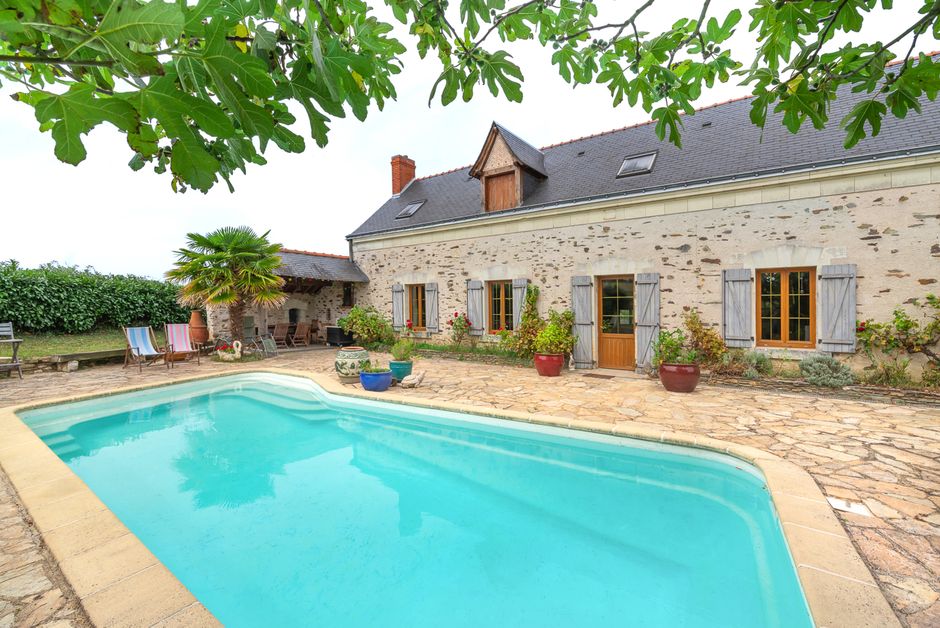Piscine enterrée avec transats devant une maison en pierre